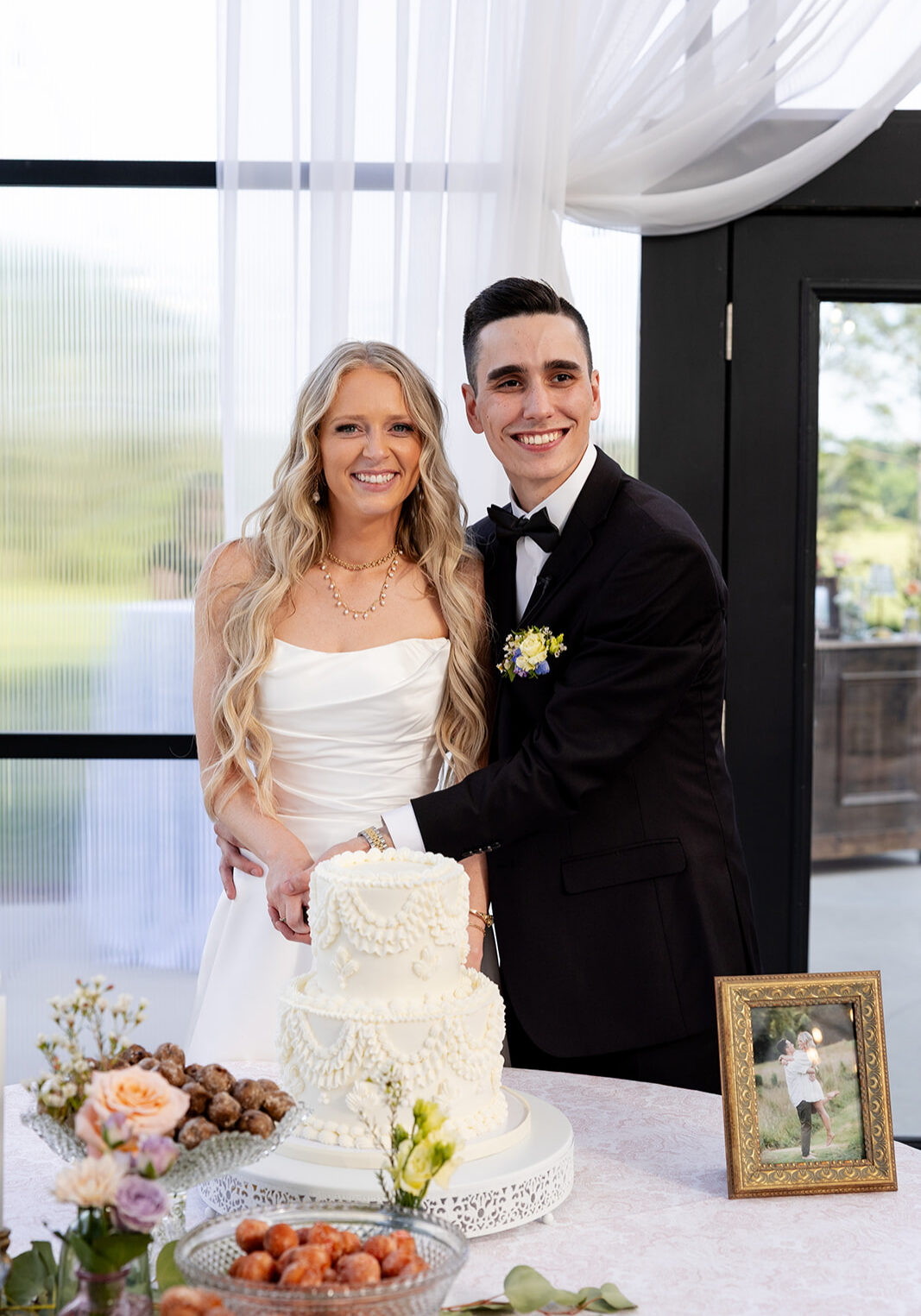 Beautiful couple at wedding cuts cake with vintage piping design at reception