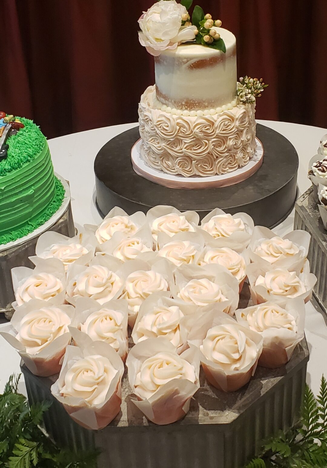 White cupcakes next to matching wedding cake at wedding reception